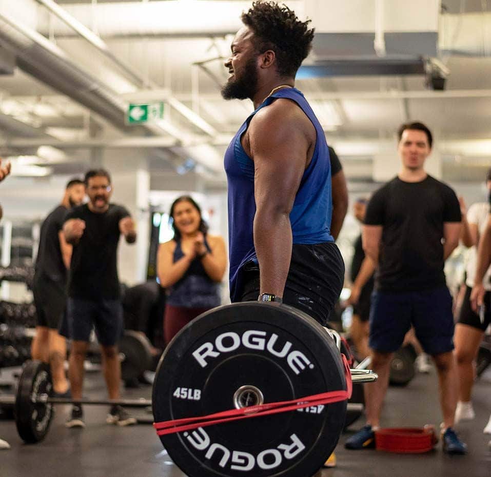 Gym member performing a lift while other members are encouraging him